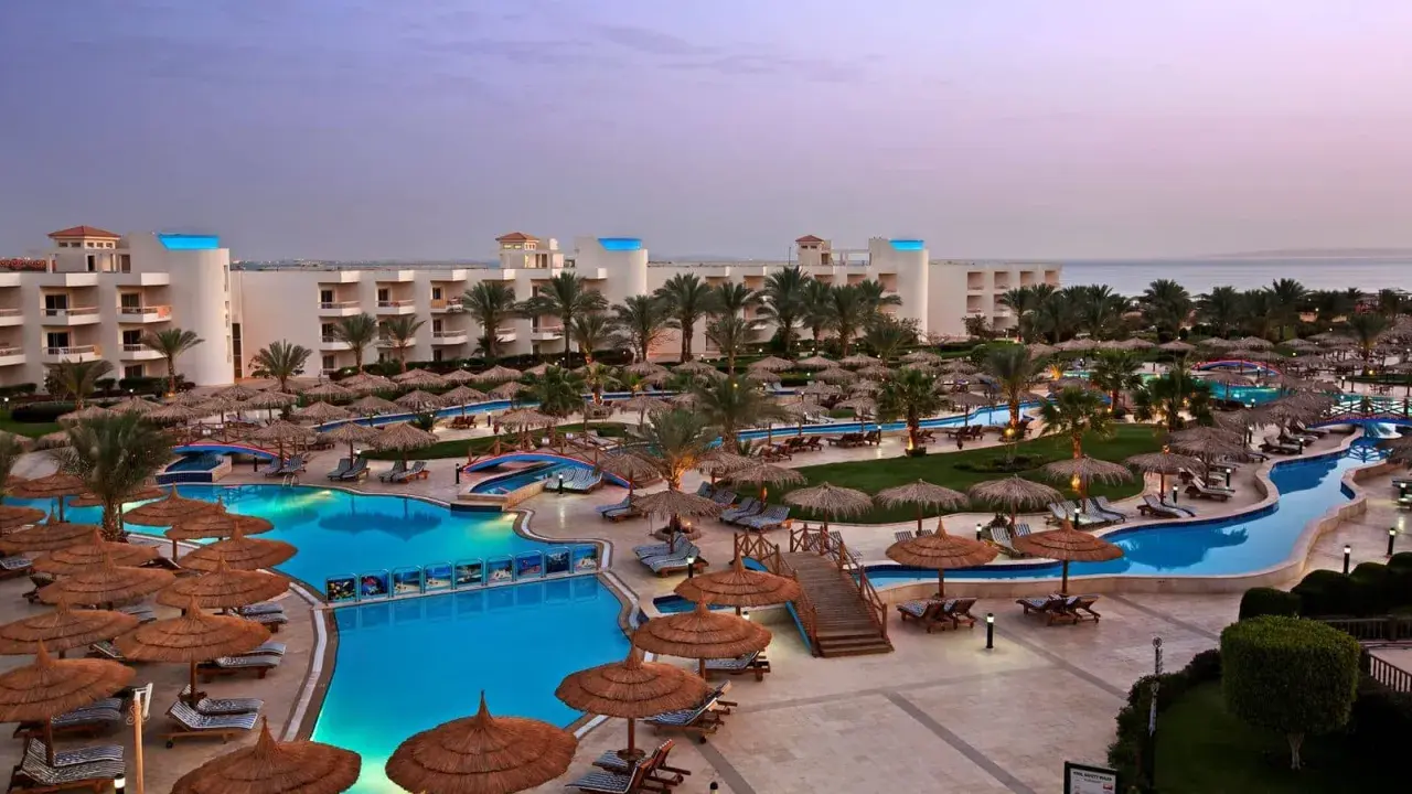 Luksusowy long beach resort Hurghada z basenami, palmami i widokiem na morze.