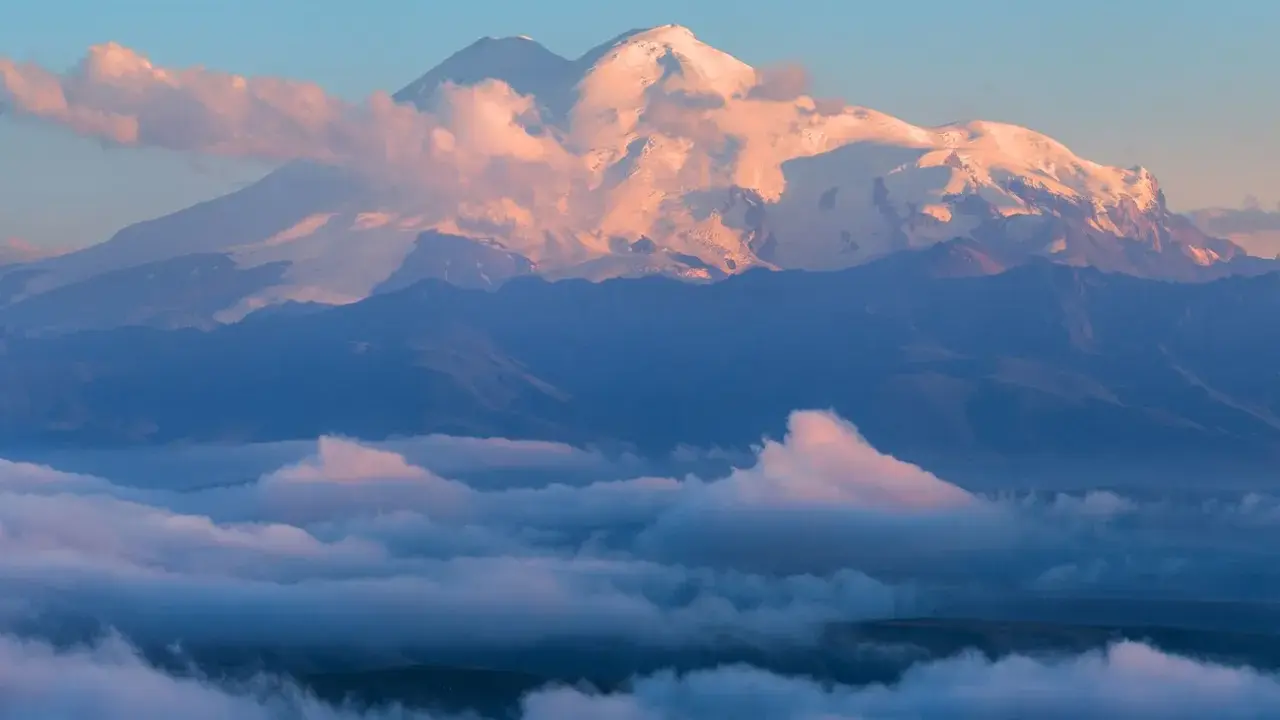 Elbrus, najwyższy szczyt Kaukazu, lśni w blasku wschodzącego słońca, otoczony morzem chmur.