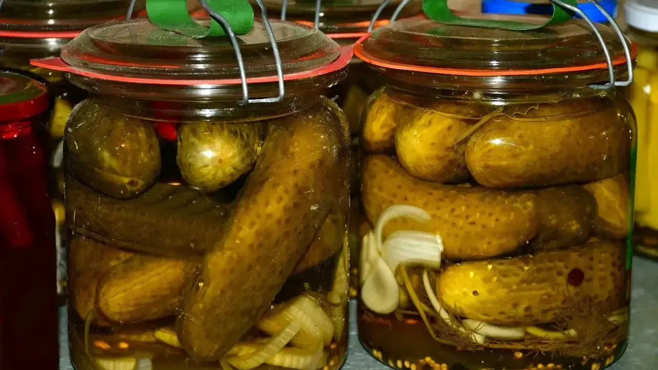 Słoiki pełne chrupiących ogórków po kaszubsku, z dodatkiem cebuli i przypraw, gotowe na zimę.