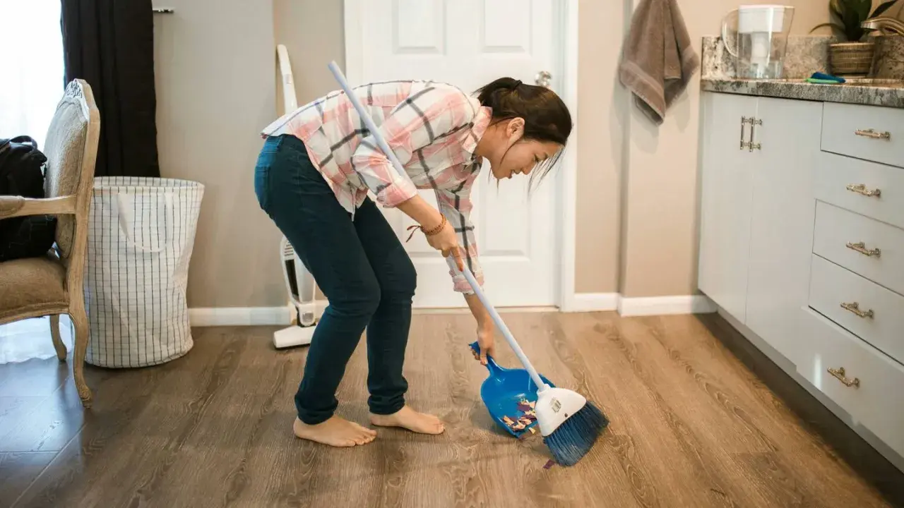 Mujer barriendo el suelo con escoba y recogedor, aplicando trucos de limpieza para mantener el hogar impecable.