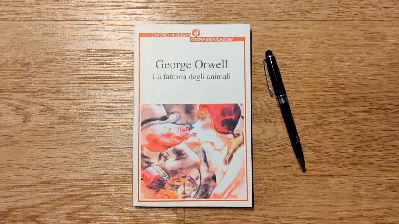 Copertina del libro "La fattoria degli animali" di George Orwell, con una penna nera appoggiata accanto.