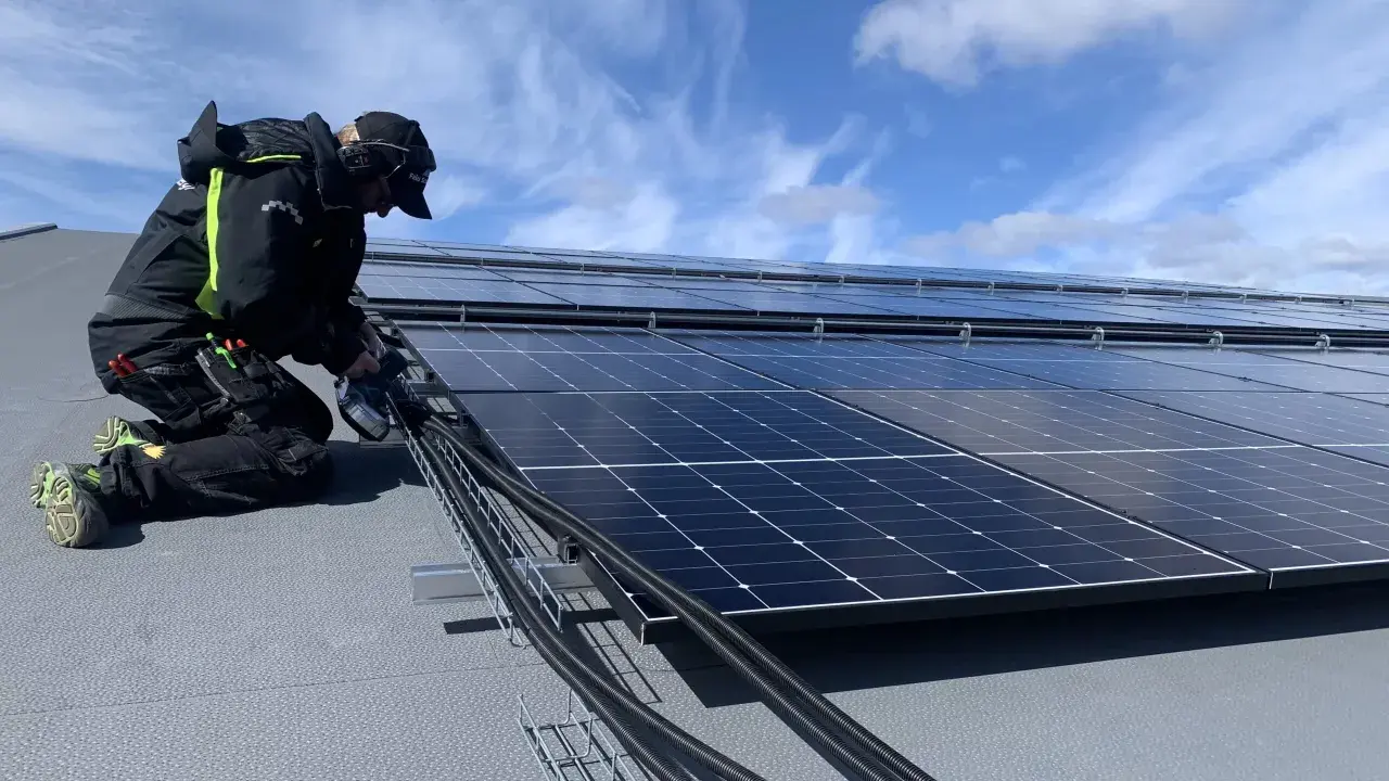 Installatör arbetar med solpaneler, drar kablar. Olika batteri storlekar kan behövas för att optimera energilagringen.