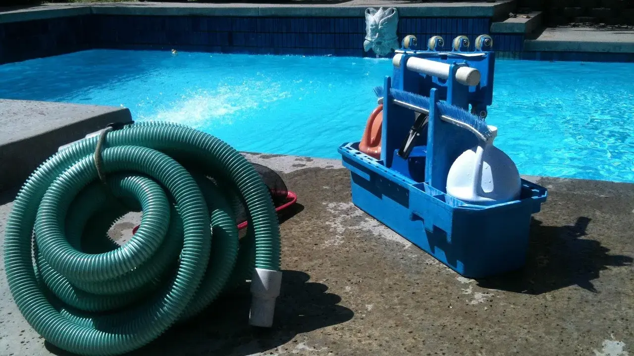 Tuyau vert enroulé et boîte bleue d'accessoires de nettoyage pour le branchement piscine.