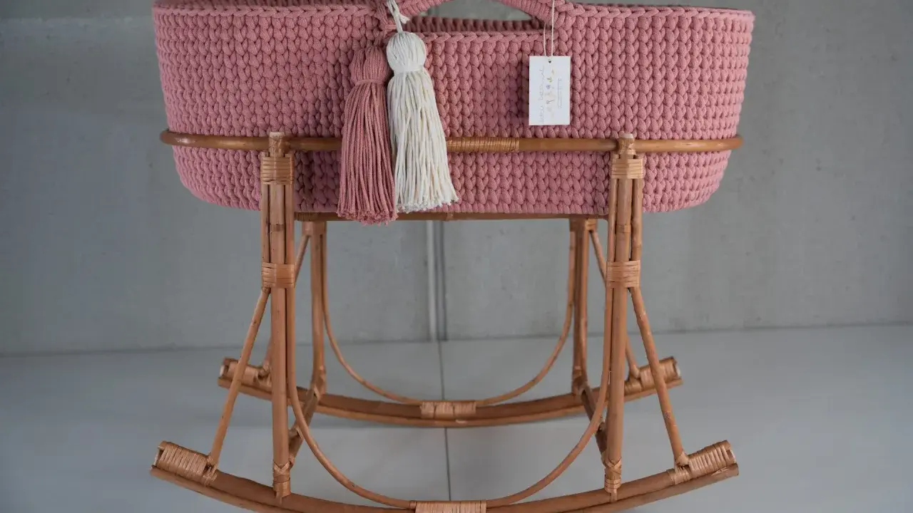 Moisés crochet rosa con borlas y base de mimbre. Un lugar acogedor para el bebé.