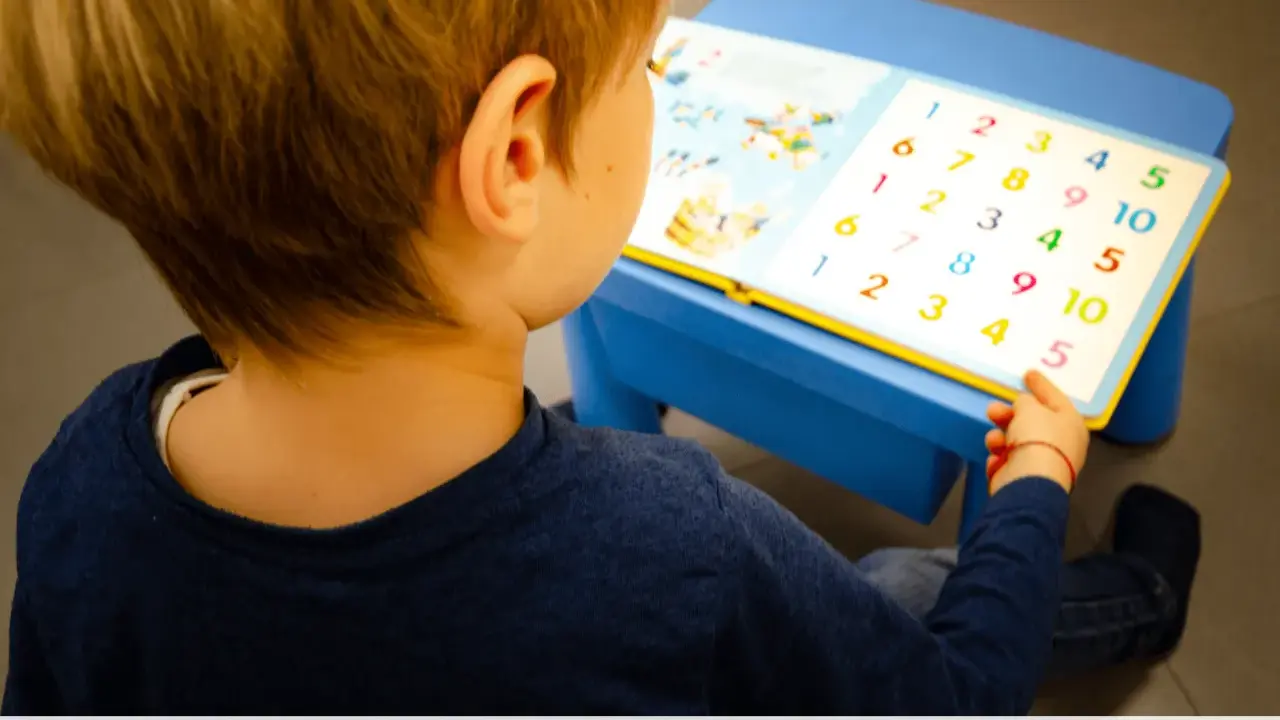 Bambino con libro di numeri colorati, parte di un test logopedia bambini.