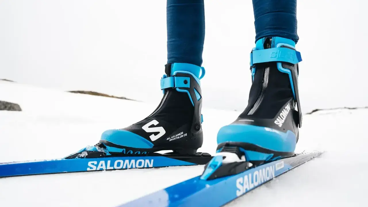 Nära bild på ett par skidpjäxor och skidor i klassisk stil, redo för en tur i snön.