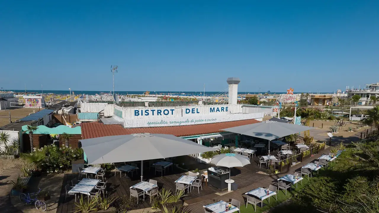 Il Bistrot del Mare a Rimini, con tavoli all'aperto e vista sulla spiaggia affollata, offre specialità romagnole.