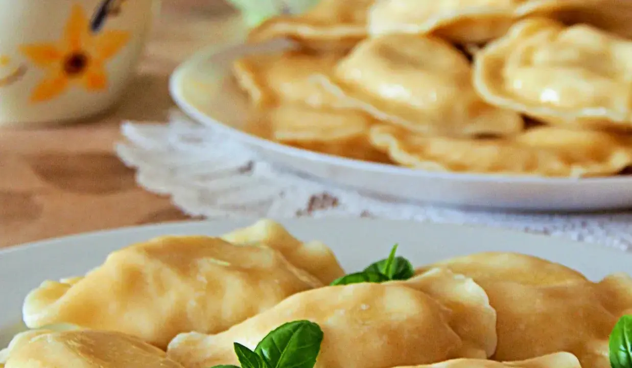 Słowackie pierogi z bryndzą na talerzu, ozdobione listkami bazylii.
