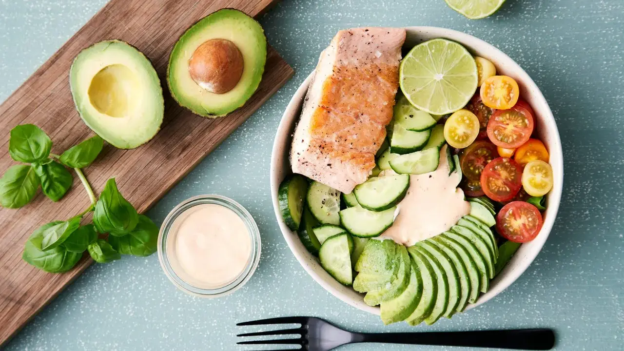 En hälsosam keto recept-bowl med lax, avokado, gurka, tomater och en krämig dressing.