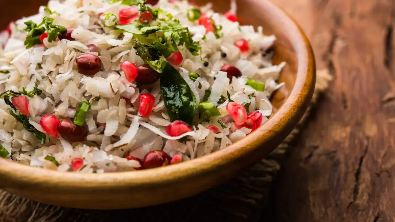 Salade de riz gastronomique, un plat coloré avec des grains de grenade, des cacahuètes et de la coriandre fraîche dans un bol en bois.