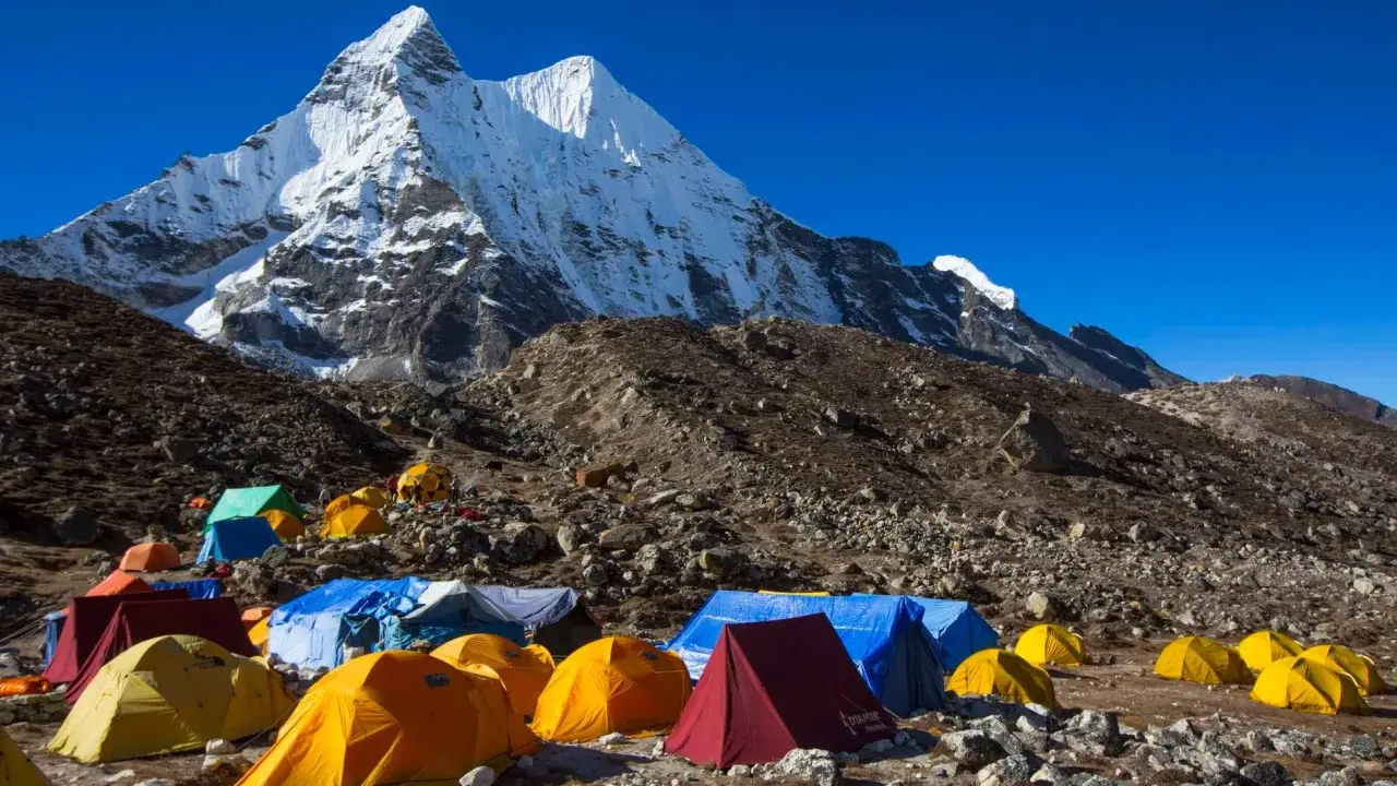Obóz pod majestatycznym szczytem Karakorum. Kolorowe namioty rozstawione na kamienistym zboczu, gotowe na przyjęcie alpinistów.