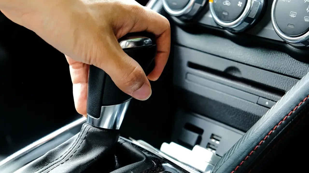 Mano operando la palanca de **cambio automático como funciona** en un coche moderno.