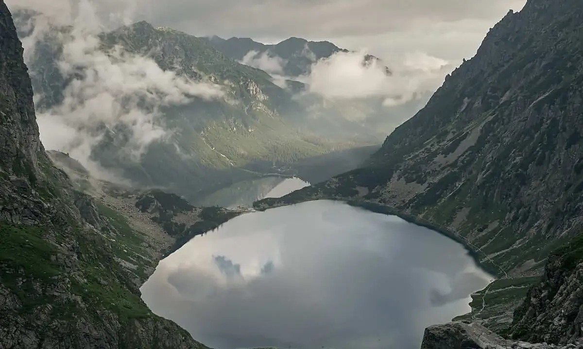 Widok na Morskie Oko, droga na Rysy w oddali. Mgła otula szczyty, odbijając się w tafli jeziora.