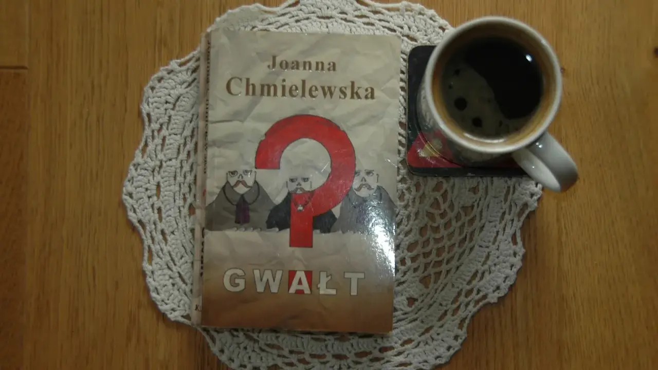 Kawa i książka Joanny Chmielewskiej "Gwałt" na koronkowym obrusie. Idealny zestaw do czytania jej kryminałów chronologicznie.