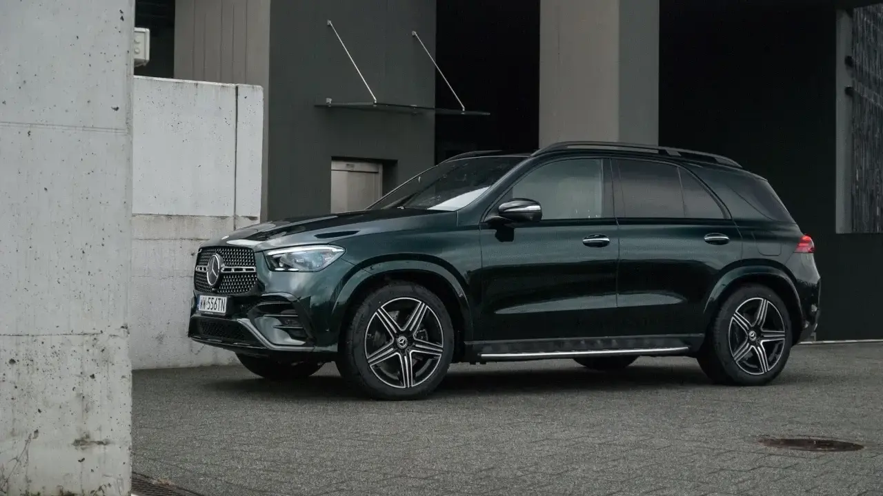 Ciemnozielony Mercedes GLE AMG stoi przed nowoczesnym budynkiem.