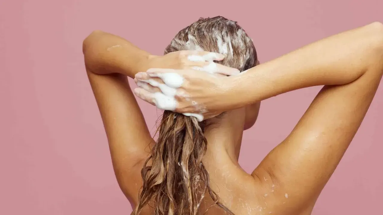 Frau wäscht sich die Haare mit Schaum. Ein Hauch von Friseur Puder für Volumen.