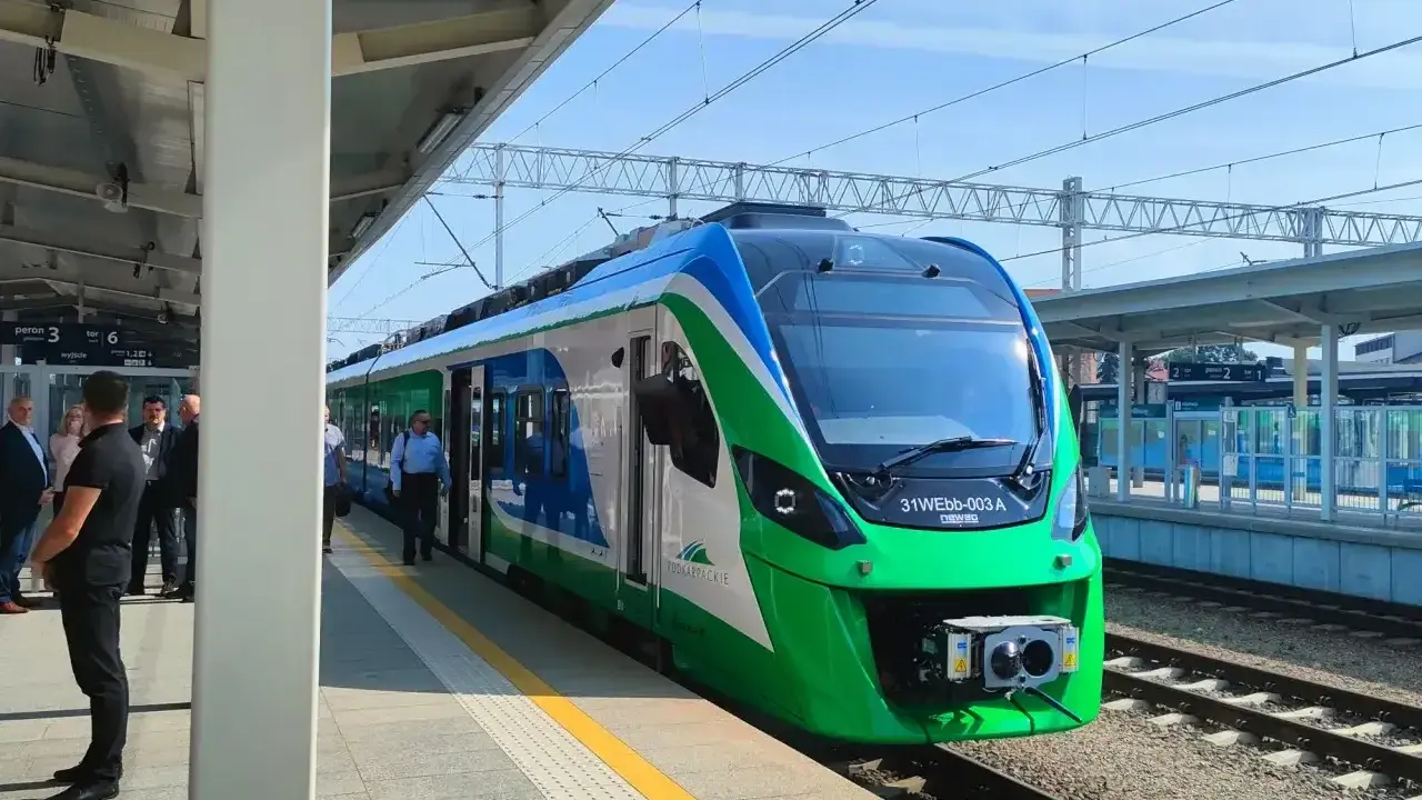Nowy pociąg na trasie Rzeszów czeka na pasażerów. Zielono-niebieski skład stoi na peronie.