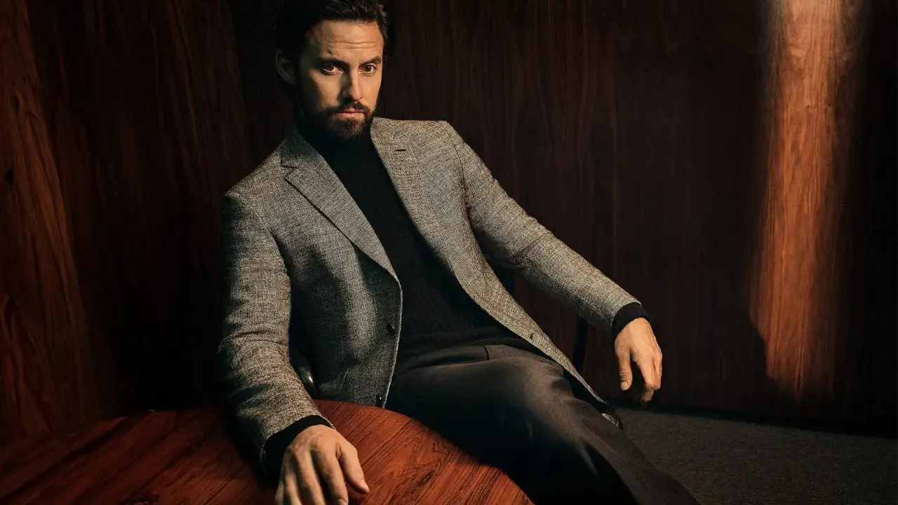 A man in a tweed blazer and dark trousers, showcasing sophisticated trouser styles.