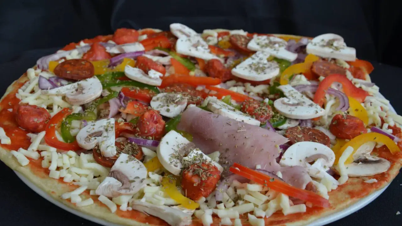 Pizza maison aux épeautre, garnie de champignons, poivrons, oignons, jambon et chorizo.