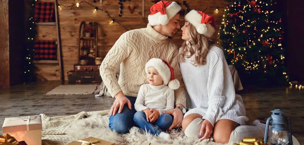 Una familia con gorros navideños, junto a un árbol de Navidad, crea una foto navidad original llena de amor y calidez.