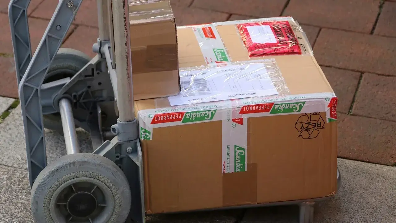 Paczki na wózku, gotowe do wysyłki. Ubezpieczenie paczki DHL to pewność, że dotrze bezpiecznie.