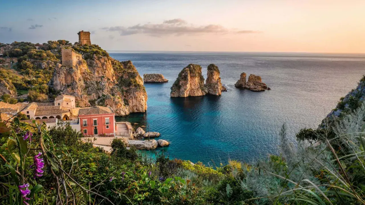 Scopri dove andare in vacanza in Italia: un borgo con torri antiche e faraglioni su un mare cristallino.