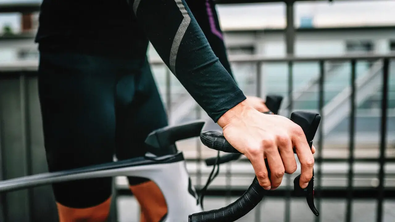 Rowerzysta z silnym bólem ud po jeździe na rowerze, trzymający kierownicę.