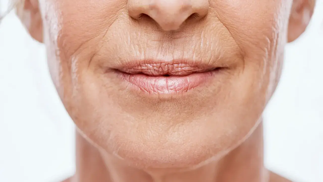 Gros plan sur le visage d'une femme, montrant les rides et ridules qui témoignent du vieillissement de la peau.