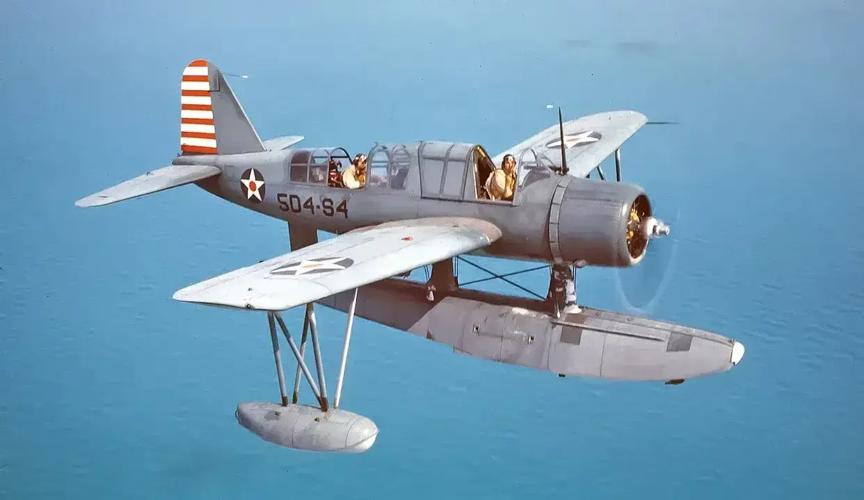Ein Wasserflugzeug mit zwei Piloten fliegt über das Meer. Die Markierungen auf dem Flugzeug sind die von siai Marchetti.