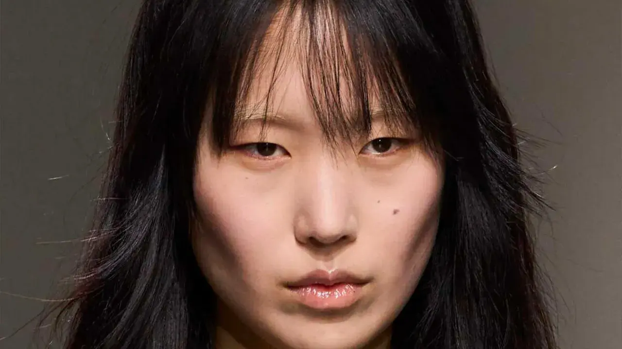 Rostro de modelo con cabello negro y flequillo desordenado, un corte **hush cut** que enmarca su rostro.