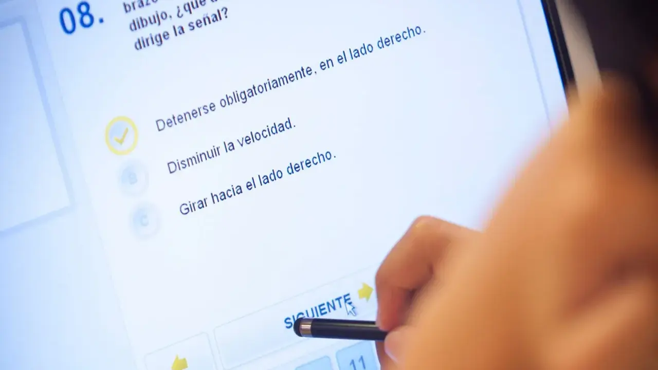 Persona haciendo un test de conducir en una tablet. La pregunta 8 es sobre una señal. ¿Cuántos test hay que hacer para aprobar el teórico?