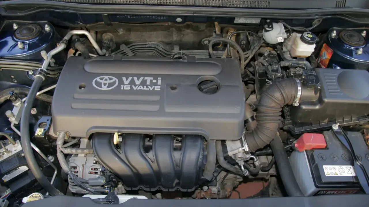 Silnik VVT-i 16 Valve z Toyoty Corolla E12. Widoczny alternator, akumulator i elementy układu dolotowego.