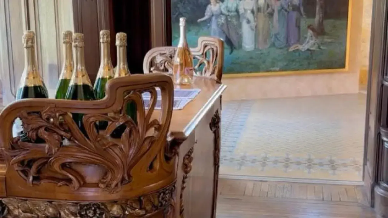 Bouteilles de champagne sur un meuble sculpté dans la maison Demoiselle à Reims. Un tableau orne le mur.