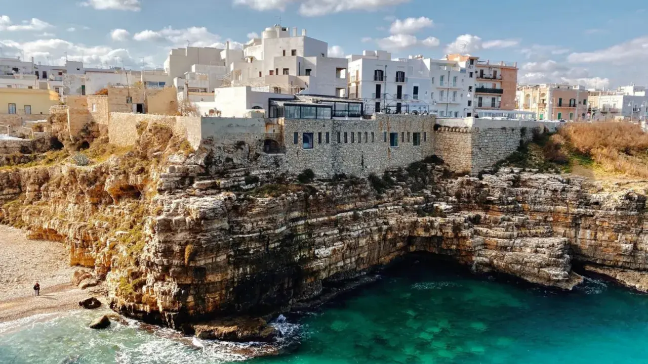 Scogliere mozzafiato e case bianche a picco sul mare turchese, perfetti **posti da visitare in Puglia estate**.