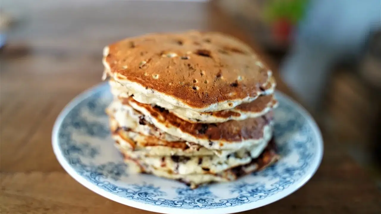 Pile de pancakes pepite chocolat sur une assiette bleue et blanche, prêts à être dégustés.