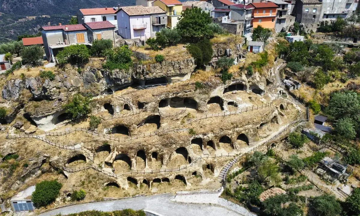 Antiche abitazioni rupestri scavate nella roccia sul Monte Poro, Calabria. Un villaggio arroccato tra le colline verdi.