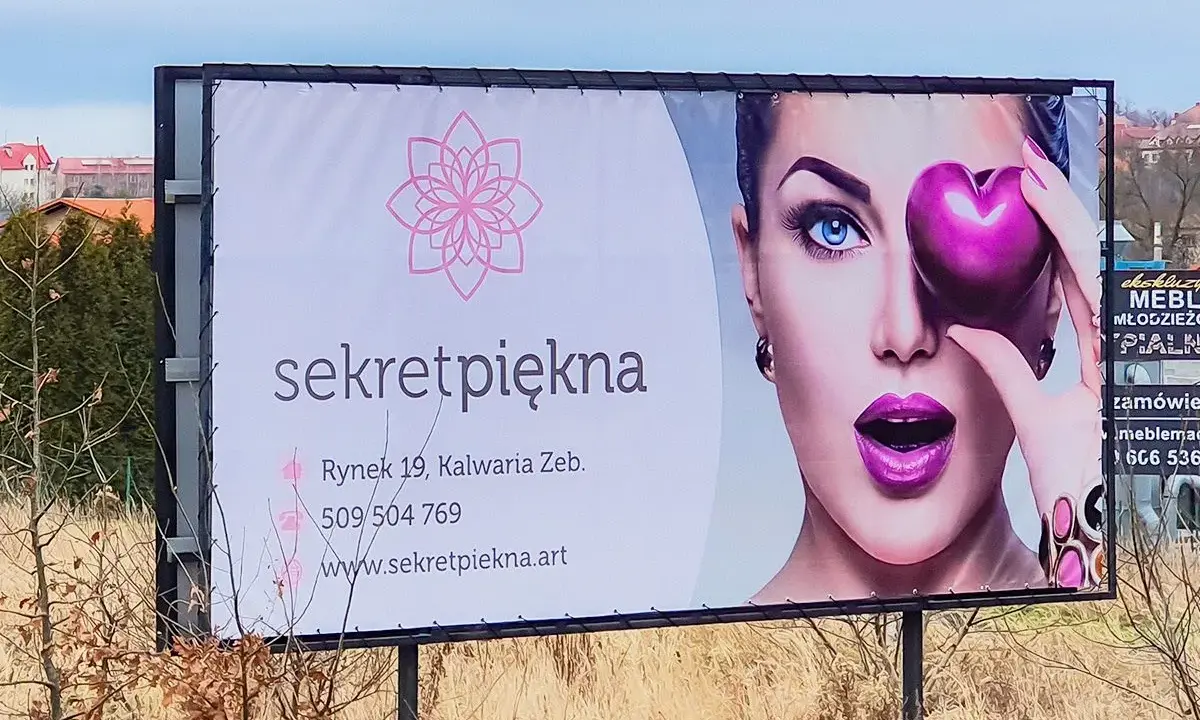 Reklama salonu "Sekret Piękna" z wizerunkiem kobiety i sercem. Personalizacja reklam pozwala dotrzeć do klientów z ofertą dopasowaną do ich potrzeb.
