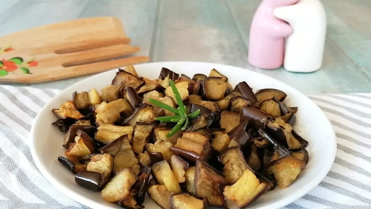 Melanzane in friggitrice ad aria, dorate e saporite, pronte per essere gustate. Un rametto di rosmarino le impreziosisce.