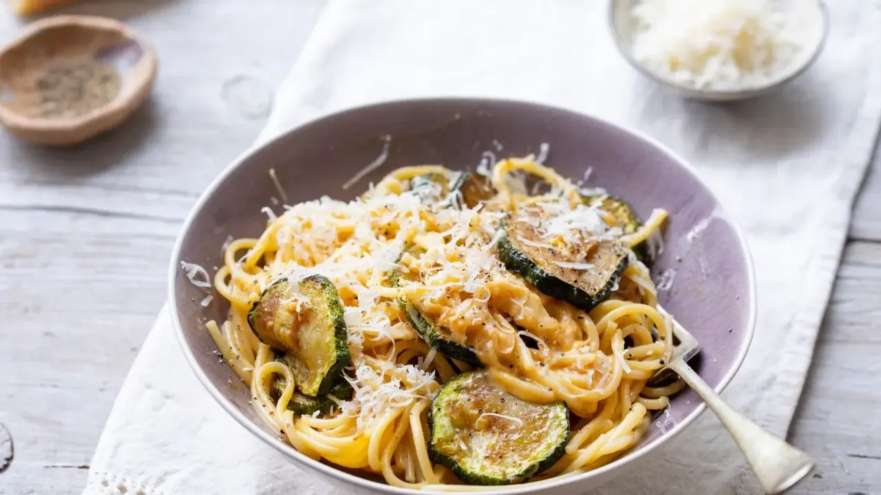 Pyszny makaron z cukinią i pieczarkami, posypany parmezanem. Idealny lekki obiad.