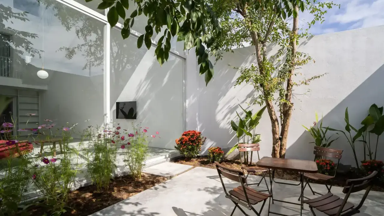 Un patio moderno con mesa y sillas de madera, flores y un árbol. ¡Excelentes ideas para porches pequeños y acogedores!