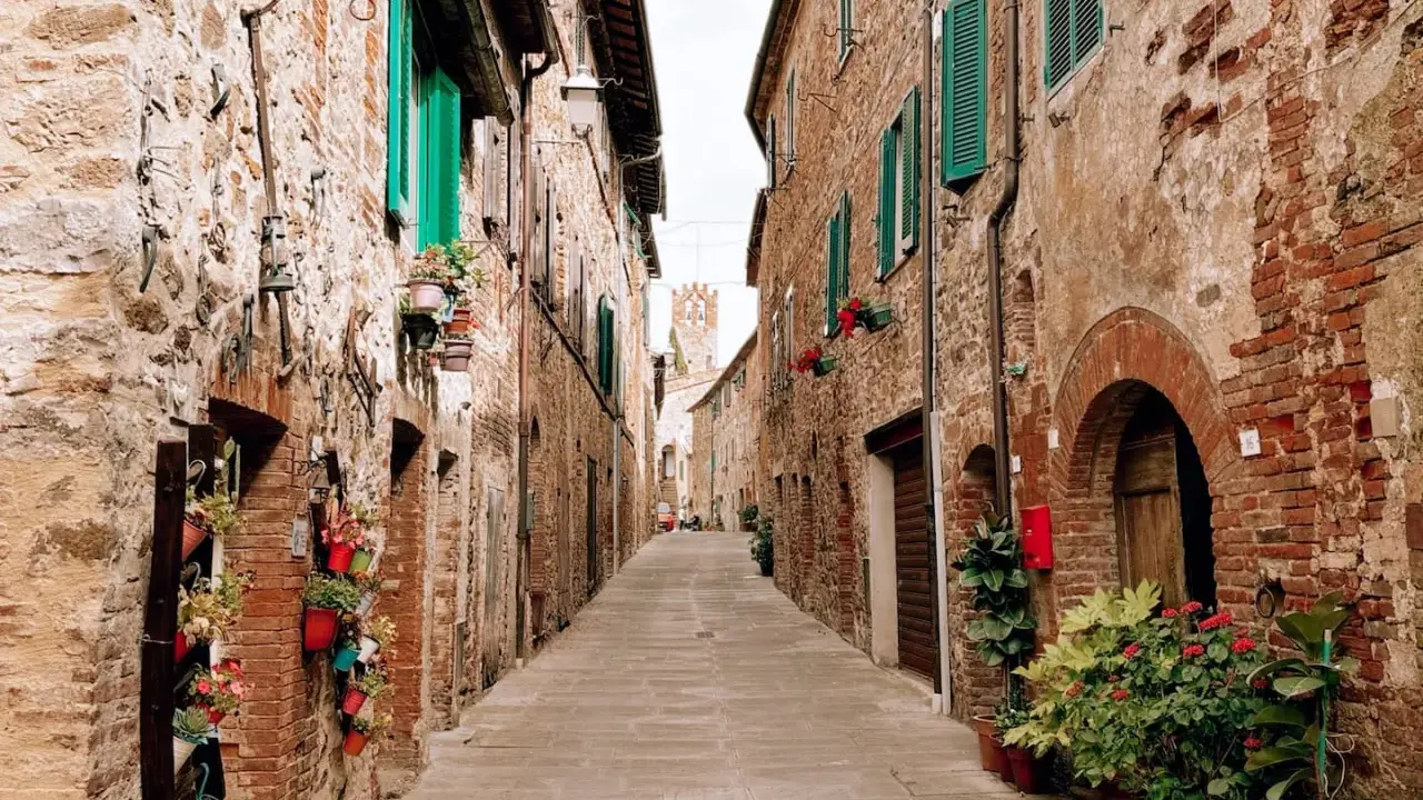 Un vicolo fiorito a Campagnatico, con case in pietra e persiane verdi. Un luogo incantevole da scoprire, tra scorci pittoreschi e storia.