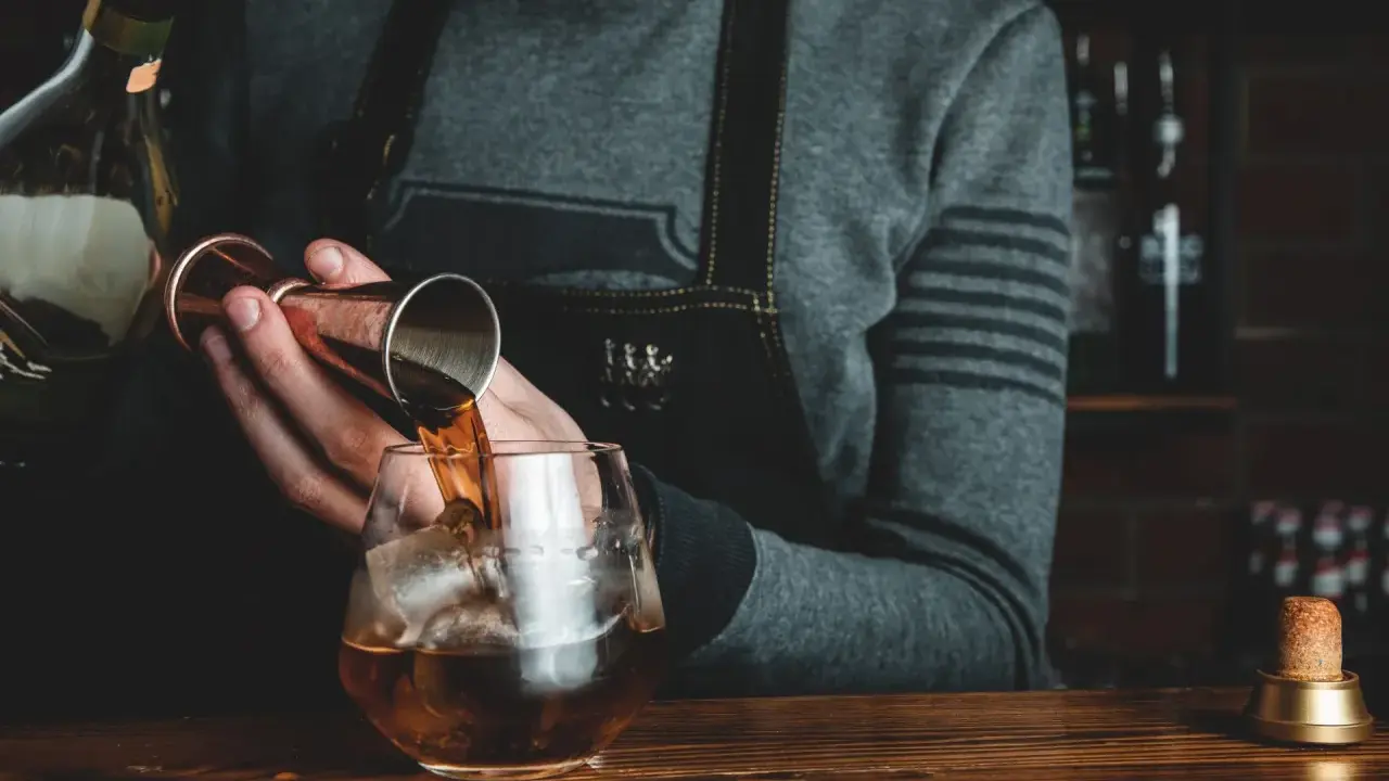 Barman nalewa whisky Glenlivet 12 do szklanki z lodem. Wiele pozytywnych opinii potwierdza jej jakość.