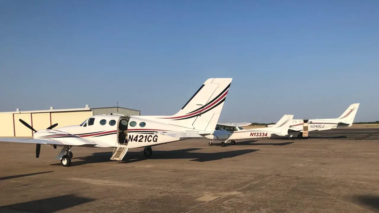 Mehrere weiße Cessna zweimotorig Flugzeuge stehen auf dem Flugplatz. Eines hat die Tür geöffnet.