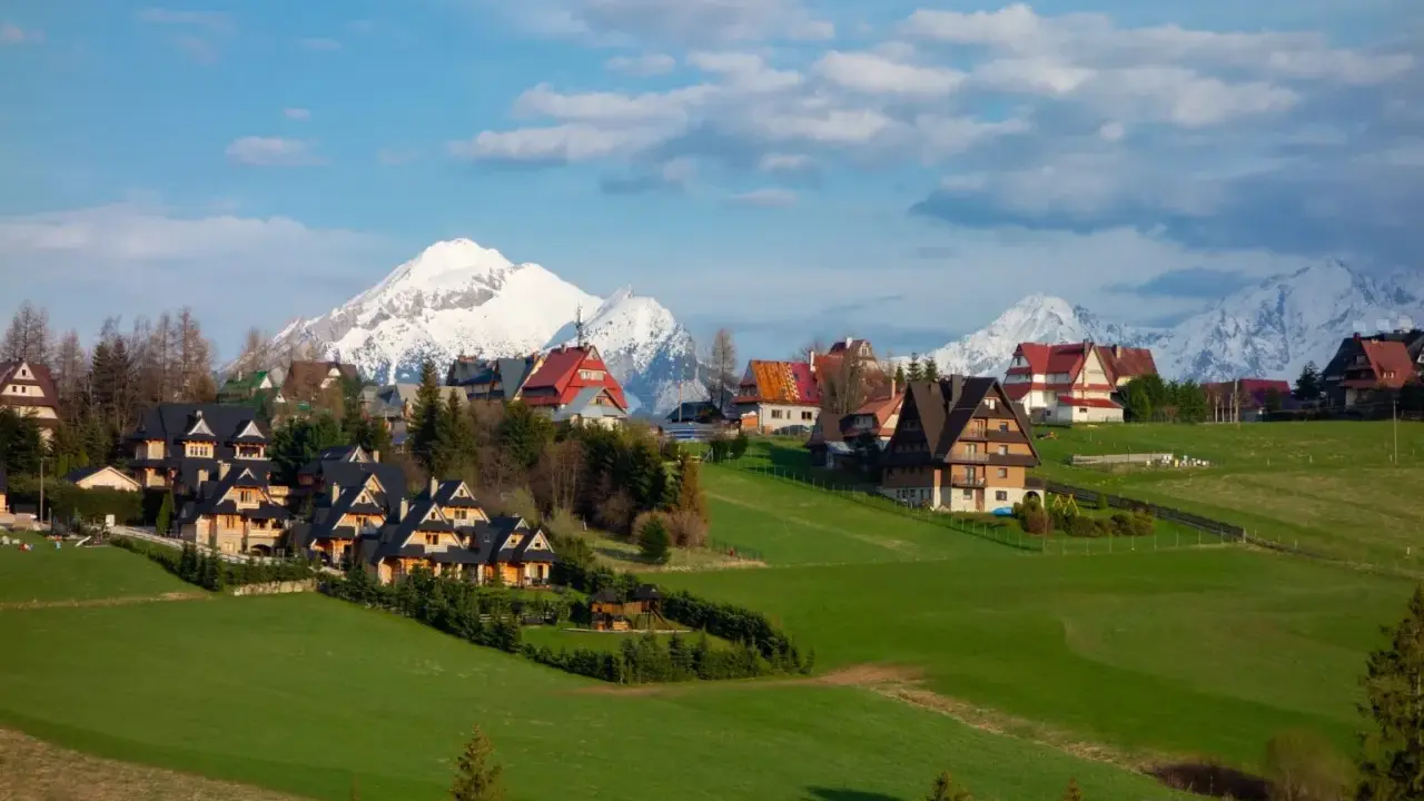Malownicze domy w Murzasichlu z widokiem na ośnieżone Tatry. Atrakcje tego miejsca to przede wszystkim piękno przyrody i spokój.