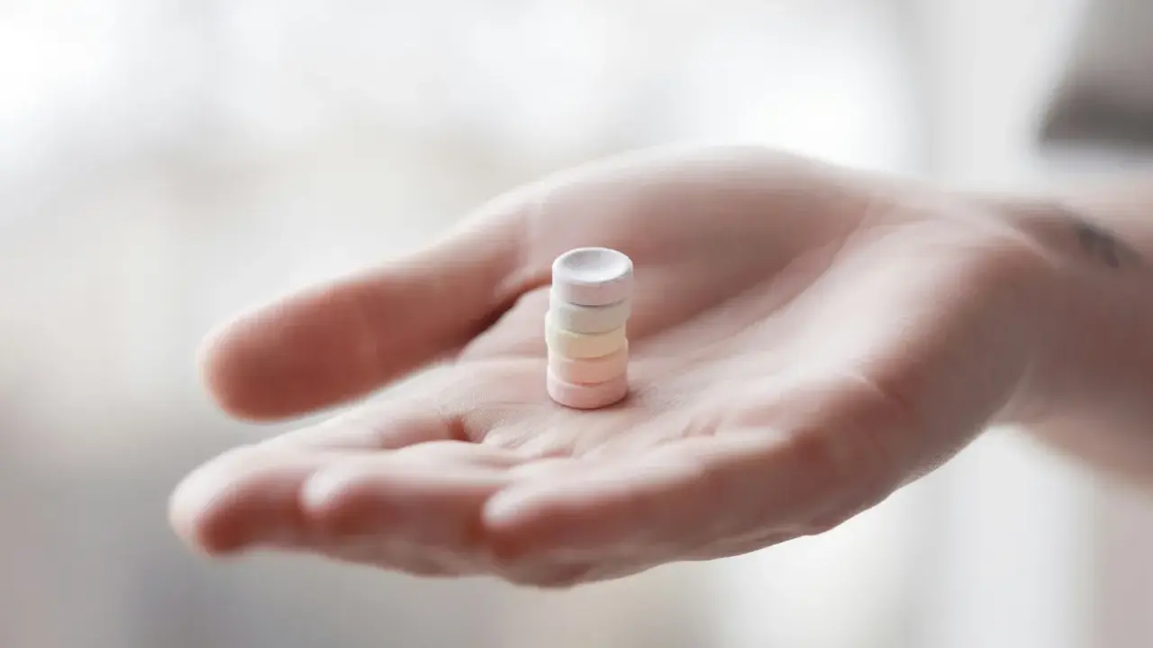 Eine Hand hält einen Stapel bunter Pillen. Vielleicht L-Arginin vor dem Schlafen für einen erholsamen Schlaf.