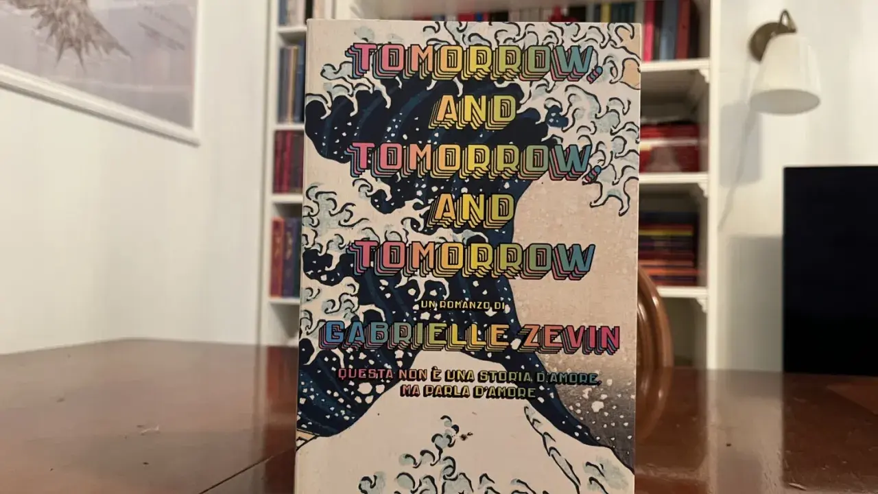 Copertina del libro "Tomorrow, and tomorrow, and tomorrow" di Gabrielle Zevin, con onde stilizzate e testo ripetuto.