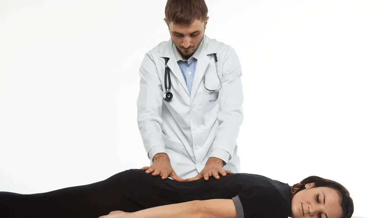 Terapeuta wykonuje delikatne ruchy na plecach pacjentki, co ilustruje, na czym polega terapia Bowen'a.