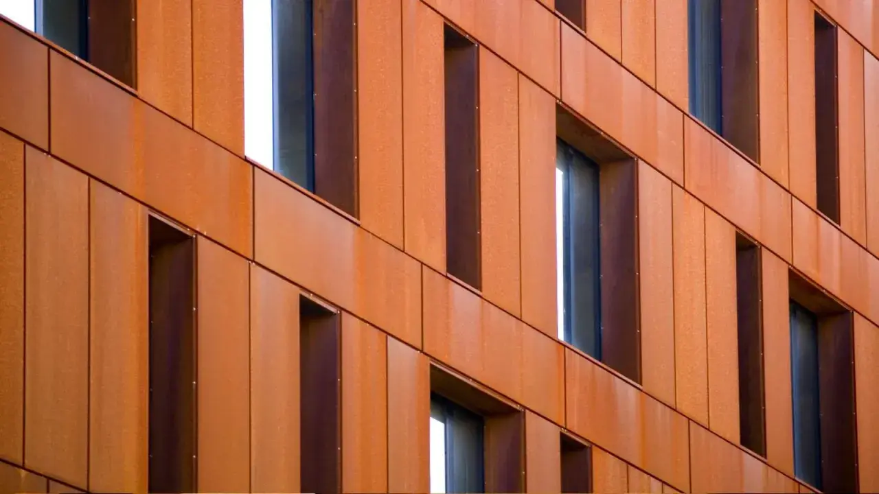 Fachada de edificio revestida con paneles de acero corten, creando un efecto oxidado y moderno.