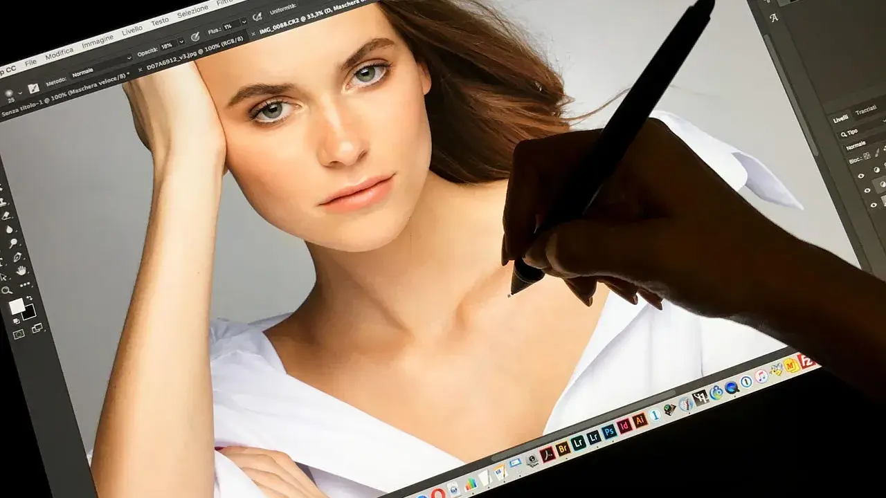 Una mano usa una tavoletta grafica per ritoccare un ritratto su Photoshop, mostrando a cosa serve questo strumento per la creatività digitale.