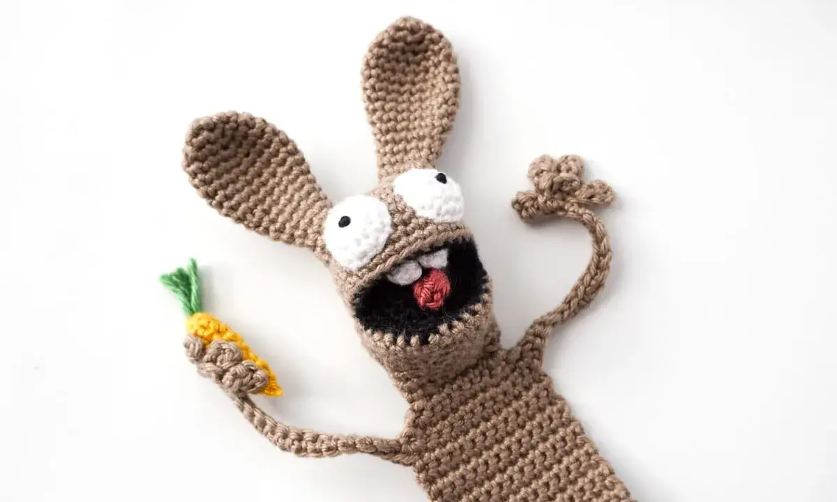 Un divertido conejo amigurumi de crochet, con ojos saltones y una zanahoria en la mano, parece listo para una aventura.